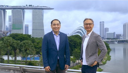 Two adult males stand in the front of Singapore landmark Marina Bay Sands.